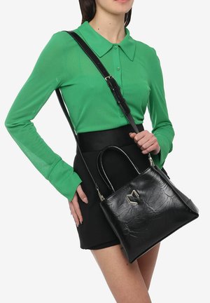 Sac à main en cuir noir au design structuré, avec une texture subtile, des poignées rondes et un accent décoratif en métal. Porté en bandoulière avec une sangle réglable.