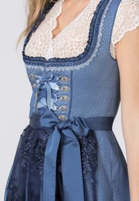 Blue dirndl dress with lace trim, ribbon accents, and floral embroidery on a sheer skirt. Includes decorative buttons and a fitted bodice.