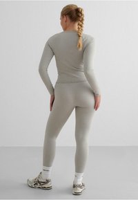 Sivi rebrasti dugih rukava i legging, bešavni dizajn, uski oblik, uparen s laganim sportskim cipelama i bijelim čarapama do članaka.