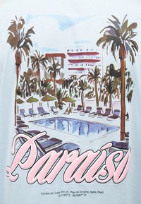 Σκηνή θέρετρου με φοίνικες, ξαπλώστρες, ομπρέλες και μια πισίνα κάτω από έναν μερικώς συννεφιασμένο ουρανό, με την επιγραφή «Παράδεισος».