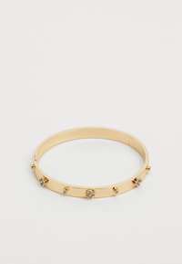 Gul metal bangle armbånd med små dekorative blomster og studs. Glat overflade med et elegant, afrundet design. Åbnes fra siden.