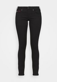 Vaqueros skinny de mezclilla negra con un corte ajustado, cinco bolsillos y cierre de botón. Textura suave con detalles de costura sutiles y acento de logo.
