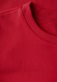 Röd sweatshirttyg med ribbad rundad halsringning. Texturen är jämn med en enhetlig yta, utan synliga mönster eller detaljer.