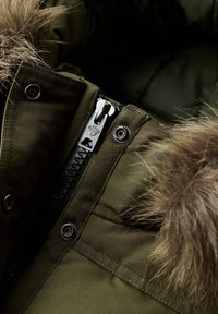 Olijfgroene parka met een afneembare bontgevoerde capuchon, voorzien van een metalen rits, drukknopen en geweven stofdetails.
