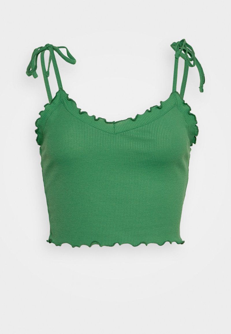 Crop top côtelé vert avec bords volantés et bretelles à nouer sur un fond clair uni.