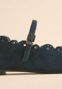 Marineblaue Wildlederschuhe mit gewelltem Rand, durchbrochenen Details und einem verstellbaren Riemen, der mit einer silbernen Schnalle gesichert ist; flache Sohle.