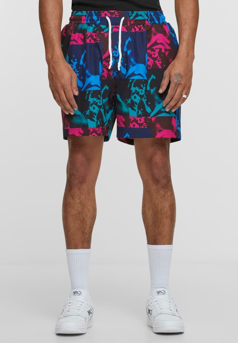 Colorful swim shorts featuring a black base with blue, pink, and teal abstract patterns. Designed with an elastic waistband and drawstring.