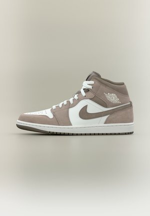 Mid-top παπούτσι Air Jordan σε λευκό και ταμπά σουέντ με λευκά κορδόνια και το λογότυπο Nike στη πλευρά, εμφανίζεται σε ουδέτερο φόντο.