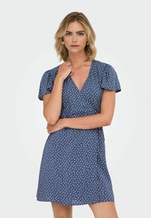 Vestido envolvente azul marino con pequeños patrones en forma de corazón blancos, mangas cortas abullonadas y escote en V. Tejido ligero, diseño hasta la rodilla.