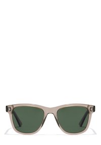 Ochelari de soare cu ramă transparentă, lentile de culoare verde închis, formă unghiulară de tip cat-eye și un mic accent cu logo pe brate.