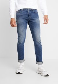 Męskie wyblakłe niebieskie dżinsy o wąskim kroju, wykonane z denimu; wyposażone w podwinięte mankiety i klasyczny design z 5 kieszeniami zapewniający funkcjonalność.