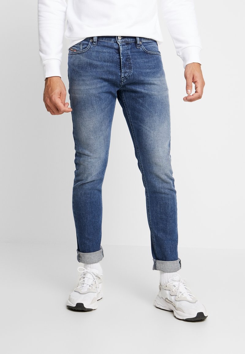 Męskie wyblakłe niebieskie dżinsy o wąskim kroju, wykonane z denimu; wyposażone w podwinięte mankiety i klasyczny design z 5 kieszeniami zapewniający funkcjonalność.