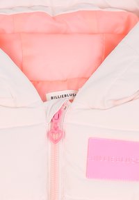 Giacca imbottita con un esterno rosa morbido, interno corallo a contrasto, tirazip a forma di cuore e un patch con logo rosa.