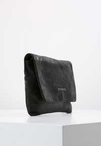 Černá psaníčko s vyvýšeným klopou, vyrobené z kůže. Disponuje hladkým povrchem a minimalistickým designem se stříbrným logem.