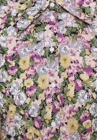 Chemise florale avec un motif de fleurs violettes, jaunes et blanches sur fond noir. Comprend des boutons blancs et un col classique.