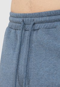 Blauwe katoenen joggingbroek met een trekkoord in de taille, gemaakt van een zachte, gestructureerde stof en voorzien van zijzakken.