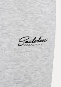 Šedá bavlněná tkanina s jemnou strukturou, která má vyšívané černé logo "Smilodox ESSENTIALS".