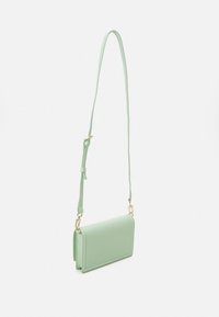 Mintgrön rektangulär crossbody-väska med justerbar rem och guldfärgade spännen, visad mot en helt vit bakgrund.