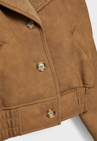 Hnědá umělá sukně z mikrovlákna s šálovým límcem, čtyřmi knoflíky, postranními kapsami a nařasením na lemování. Měkká textura a strukturovaný design.