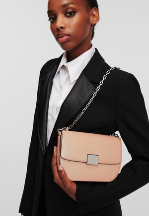 Borsa a tracolla in pelle rosa chiaro con tracolla in catena argento, forma rettangolare e chiusura magnetica. Design semplice con minimi accessori hardware.