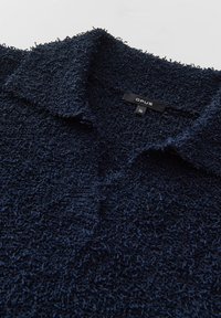 Polo en bleu marine texturé avec une surface douce et pelucheuse, doté d'un col classique et d'une étiquette indiquant "OPUS" et la taille "36".