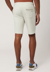 Lichtgrijze shorts van zachte stof, met een elastische tailleband en een enkele achterzak met een decoratieve stikseldetails.