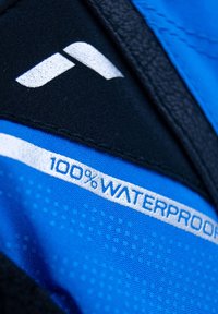 Wasserdichte Jacke in Blau und Schwarz. Ausgestattet mit einem strukturierten Stoff und einem silbernen Etikett "100% WASSERDICHT" sowie einem markanten Logodesign.