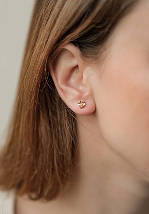 Goldfarbene, blumenförmige Ohrstecker mit kleinen Blütenblättern. Das Design ist zart und zeigt eine polierte, reflektierende Oberfläche.