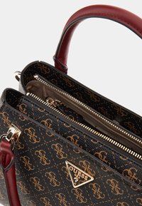Black synthetic handbag with gold logo pattern and maroon leather accents. Features two zippered compartments and a structured shape.