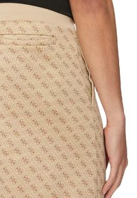 Falda beige con un patrón de logotipos en rojo y marrón. Cuenta con un bolsillo lateral y una textura suave con una cinturilla ligeramente elástica.