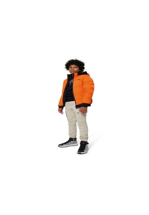 Doudoune orange avec accents noirs, sweat à capuche noir en dessous, pantalon beige et baskets noires avec des détails blancs.