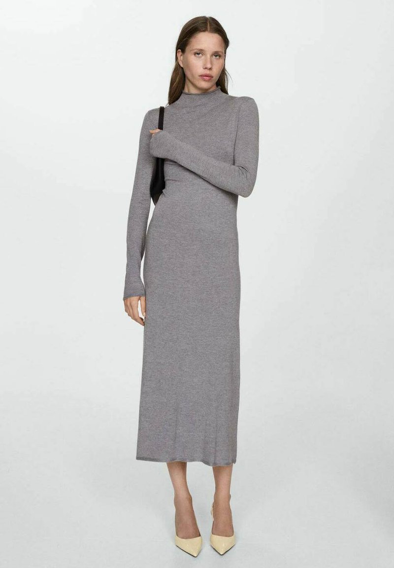 Robe grise à manches longues, avec un col haut et une coupe ajustée. Dotée d'une texture tricot douce, elle atteint le mollet et se marie avec des talons clairs.