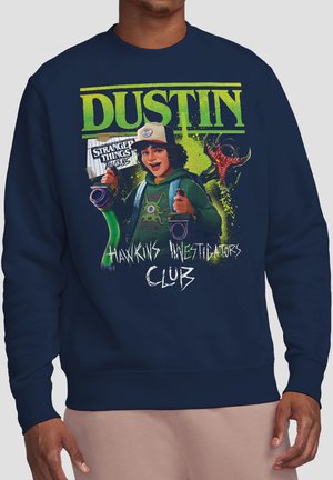 Sweatshirt mit der Figur Dustin aus Stranger Things, der Walkie-Talkies hält, mit dem Text "Hawkins Investigators Club" und grünem Monster-Hintergrund.
