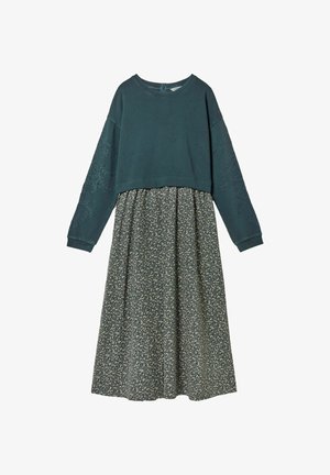 Dunkelgrünes Langarmoberteil mit Lochstickerei an den Ärmeln, kombiniert mit einem hoch taillierten, dunkel geblümten Midirock.