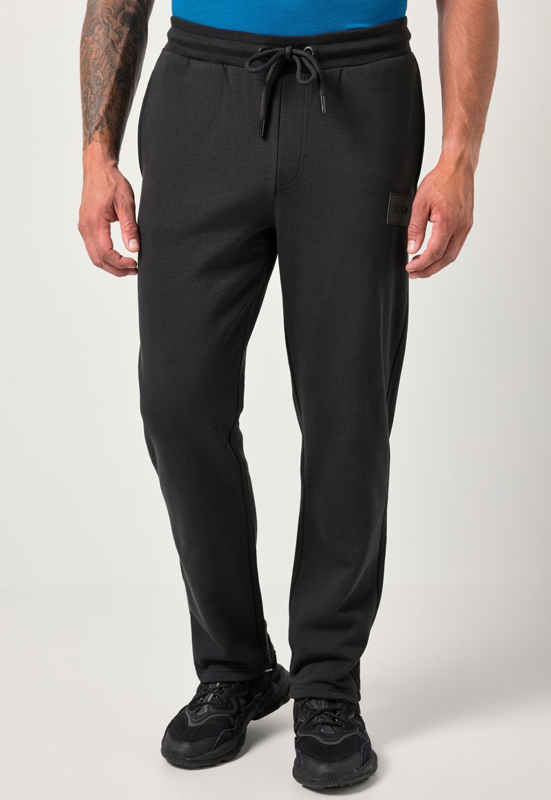 Zwarte joggers met een elastische tailleband, trekkoord en zijzakken. De stof heeft een gladde textuur en is voorzien van een logo label aan de voorkant.