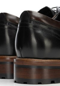 Czarne skórzane buty o gładkim wykończeniu, z drewnianą podeszwą z ciemnymi akcentami i widocznym przeszyciem na pięcie.