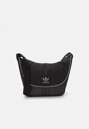 Sac à épaule noir Adidas avec une sangle réglable, un panneau avant inférieur en mesh et un marquage réfléchissant sur tissu supérieur lisse.