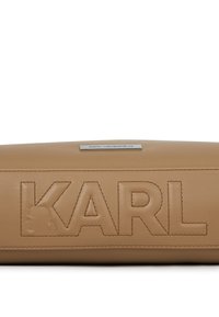 Barna bőr pénztárca, amelyen a "KARL" felirat és logó van a bőrbe nyomva. Horizontális forma, sima tekstúra és varrott részletek jellemzik. Ezüst színű fém kiegészítők.