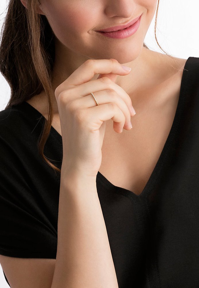 Goldring mit strukturierter Gestaltung, getragen an der Hand eines Models. Das Model trägt ein schwarzes V-Ausschnitt-Top.