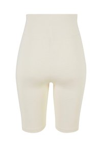 Beige high-waisted fietsbroekjes van rekbaar materiaal. Soepele textuur met een naadloos ontwerp, eindigend net boven de knie.