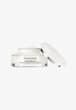 Bocal en verre clair, rond, avec un couvercle en crème blanche et accents argentés. L'étiquette indique "Elizabeth Arden Visible Difference Refining Moisture Cream Complex."