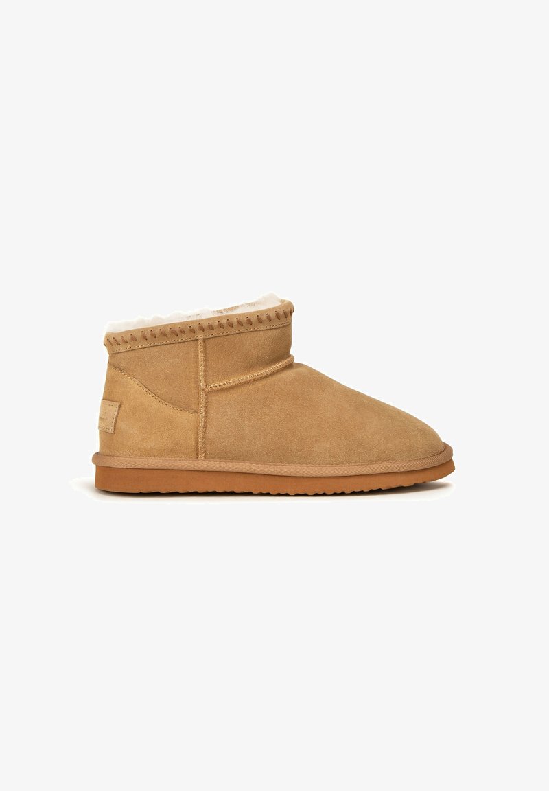 Short tan suede ankle boot with stitched detailing, flat rubber sole, and white fluffy inner lining visible at the top.