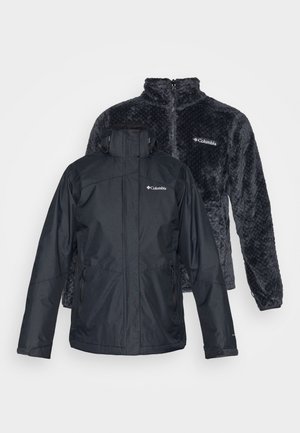 Zwarte waterdichte jas met meerdere ritszakken en een sluiting aan de voorkant. Daarachter een donkergrijze fleecejas met een gestructureerd patroon en hoge kraag.