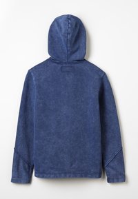 Felpa con cappuccio di colore blu navy, realizzata in un tessuto morbido e textured. Presenta un design semplice, cappuccio arrotondato e maniche lunghe con dettagli a costine.