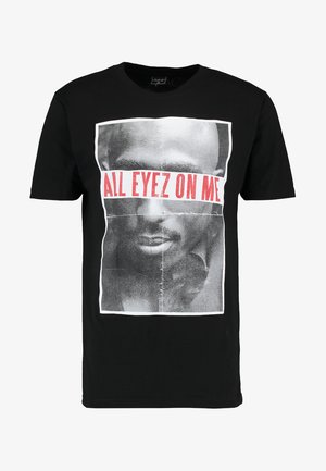 Čierne bavlnené tričko s grafickým potlačou tváre a textom "VŠETKY OČI NA MNE" v tučnej červenej farbe. Krátke rukávy a okrúhly výstrih.