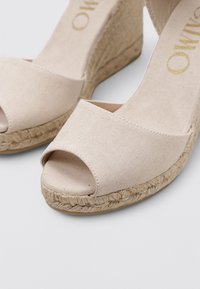 Sandalias de cuña de lienzo beige con punta abierta y plataforma de yute trenzado. Parte superior texturizada y detalle de plantilla suave.