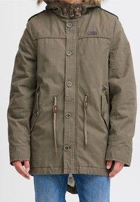 Olijfgroene parka met een capuchon gevoerd met bont, knoopsluitingen, trekkoorden in de taille en twee zijzakken.