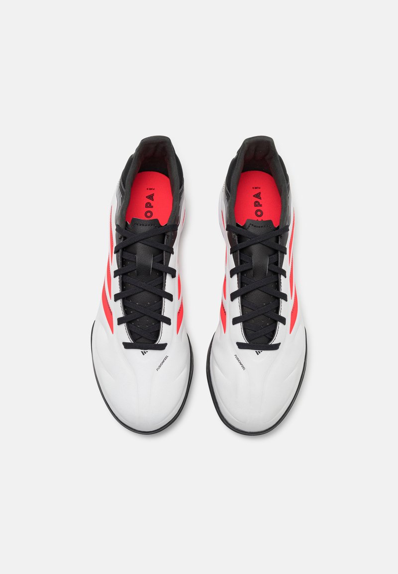 Weiße Sportschuhe mit schwarzen Schnürsenkeln und Akzenten, mit roten Details an den Seiten, glatter Textur und einem schlanken Design.
