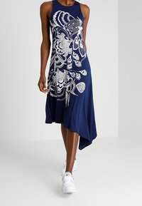 Granatowa, bezrękawnikowa sukienka z asymetrycznym dołem, zdobiona białymi haftami w kwiatowy wzór. Wykonana z miękkiej, lekkiej tkaniny.
