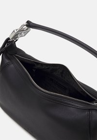 Sac à main en cuir noir avec des garnitures en argent, doté d'une fermeture éclair et d'un intérieur avec doublure logo. Le design est élégant et épuré.